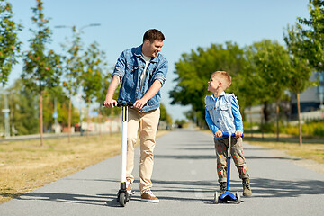 Image showing father and little son riding scooters in city