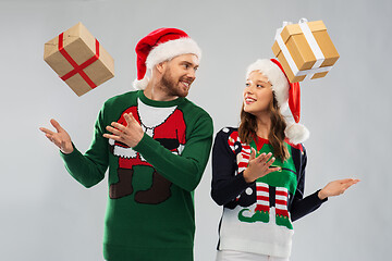 Image showing happy couple in christmas sweaters with gifts