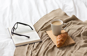 Image showing coffee, croissant, blanket and book on bed at home