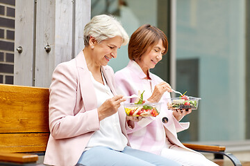 Image showing senior women eating takeaway food on city street