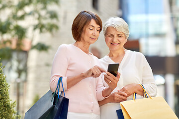 Image showing old women with shopping bags and cellphone in city