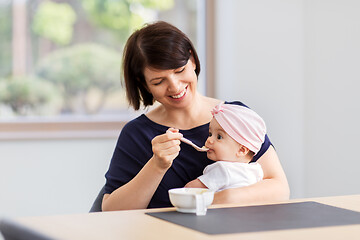 Image showing middle-aged mother feeding baby daughter at home