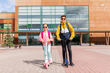 Image showing school children with backpacks riding scooters