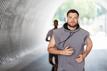 Image showing male friends with headphones running outdoors