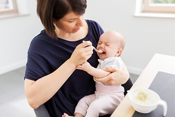 Image showing middle-aged mother feeding baby daughter at home