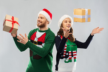 Image showing happy couple in christmas sweaters with gifts