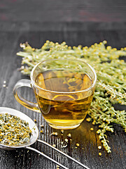 Image showing Tea of gray wormwood in glass cup with strainer on black board