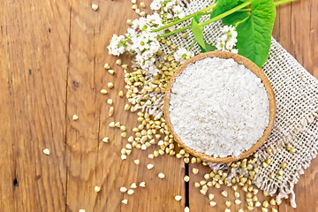 Image showing Flour buckwheat green in bowl with flowers on old board top