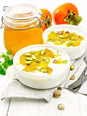 Image showing Dessert of yogurt and persimmon two bowls on light wooden board