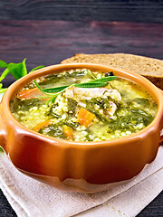 Image showing Soup with couscous and spinach in clay bowl on dark board