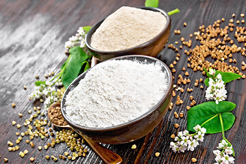 Image showing Flour buckwheat green and brown in bowls with flowers on wooden 