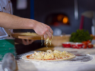 Image showing chef sprinkling cheese over fresh pizza dough