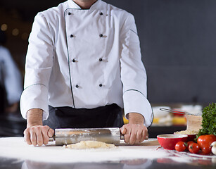 Image showing chef preparing dough for pizza with rolling pin