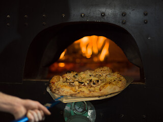 Image showing chef removing hot pizza from stove