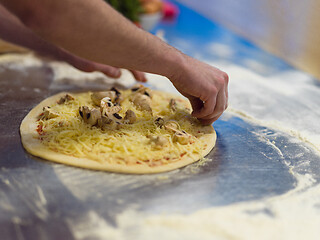 Image showing chef putting fresh mushrooms on pizza dough