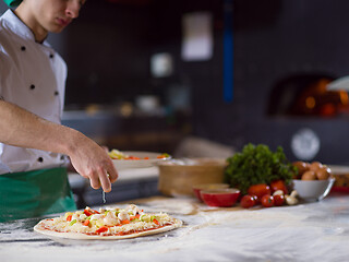 Image showing chef putting fresh vegetables on pizza dough