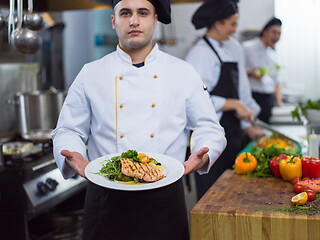 Image showing Chef holding dish of fried Salmon fish fillet