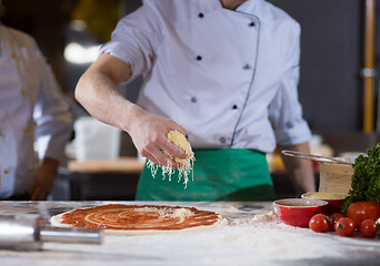 Image showing chef sprinkling cheese over fresh pizza dough