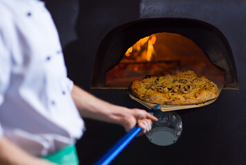 Image showing chef removing hot pizza from stove