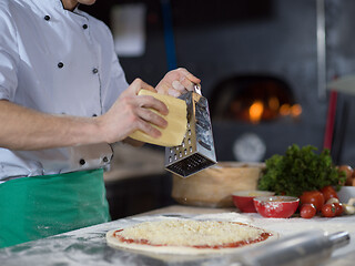 Image showing chef sprinkling cheese over fresh pizza dough