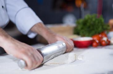 Image showing chef preparing dough for pizza with rolling pin