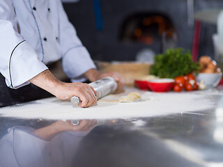 Image showing chef preparing dough for pizza with rolling pin