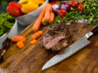 Image showing Juicy slices of grilled steak on wooden board