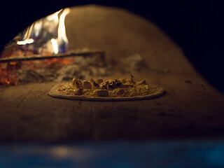 Image showing chef putting delicious pizza to brick wood oven