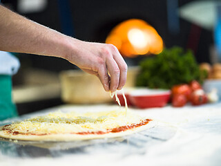 Image showing chef sprinkling cheese over fresh pizza dough