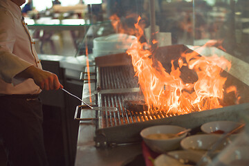 Image showing chef cooking steak with vegetables on a barbecue