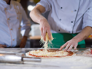 Image showing chef sprinkling cheese over fresh pizza dough