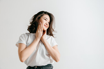 Image showing Happy asian woman standing and smiling against gray background.