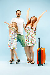 Image showing Happy parent with daughter and suitcase at studio isolated on blue background