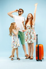 Image showing Happy parent with daughter and suitcase at studio isolated on blue background