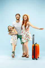 Image showing Happy parent with daughter and suitcase at studio isolated on blue background