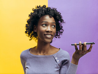 Image showing Indoor portrait of attractive young black woman holding blank smartphone