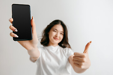 Image showing Portrait of a confident casual asian girl showing blank screen of mobile phone