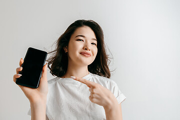 Image showing Portrait of a confident casual asian girl showing blank screen of mobile phone