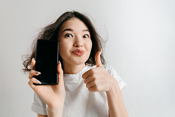 Image showing Portrait of a confident casual asian girl showing blank screen of mobile phone