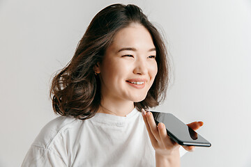 Image showing Indoor portrait of attractive young asian woman holding blank smartphone