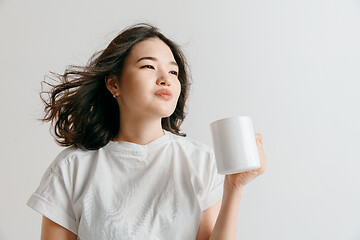 Image showing Taking a coffee break. Handsome young man holding coffee cup while standing against gray background