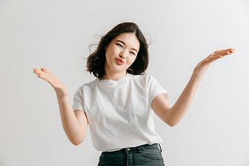 Image showing The happy asian woman standing and smiling against gray background.