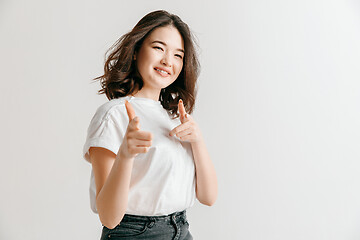 Image showing The happy asian woman standing and smiling against gray background.