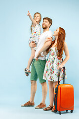 Image showing Happy parent with daughter and suitcase at studio isolated on blue background