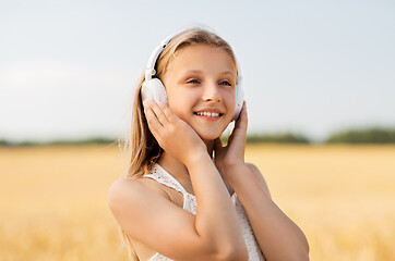 Image showing happy girl in headphones on cereal field in summer