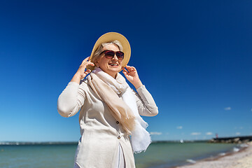 Image showing happy senior woman in sunglasses and hat on beach