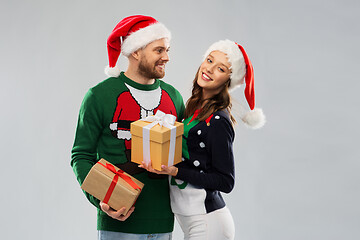 Image showing happy couple in christmas sweaters with gifts