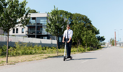 Image showing young businessman riding electric scooter outdoors