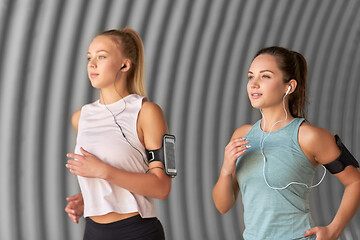 Image showing young women with earphones and smartphones running