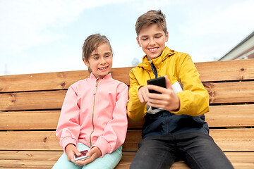 Image showing children with smartphones sitting on street bench